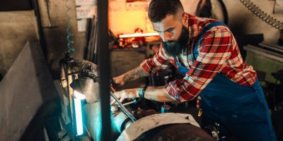 A tattooed production worker operating a machine and producing goods. A tattooed production worker operating a machine and producing goods.