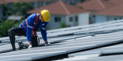 A technician is installing solar panels on the roof of the warehouse A technician is installing solar panels on the roof of the warehouse