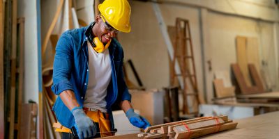 African American carpenter man look happy to work with timber in factory workplace