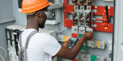 Electrician checking voltage in switchgear at solar station Electrician checking voltage in switchgear at solar station