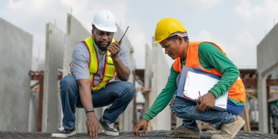 Foreman and laborer check steel reinforcement cage for make precast wall in construction site.