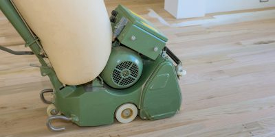 Wooden parquet floor being ground by carpenter using floor sander in a newly constructed home Wooden parquet floor being ground by carpenter using floor sander in a newly constructed home